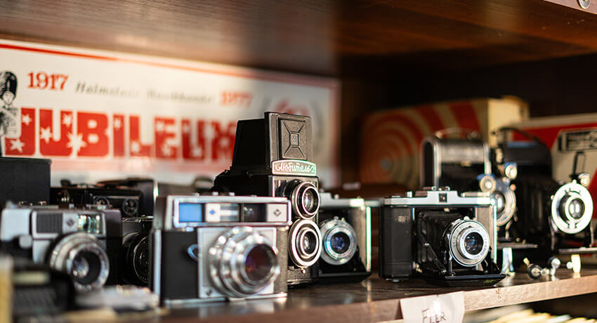 En närbild på fett lertal svarta vintage-kameror som står på en hylla.