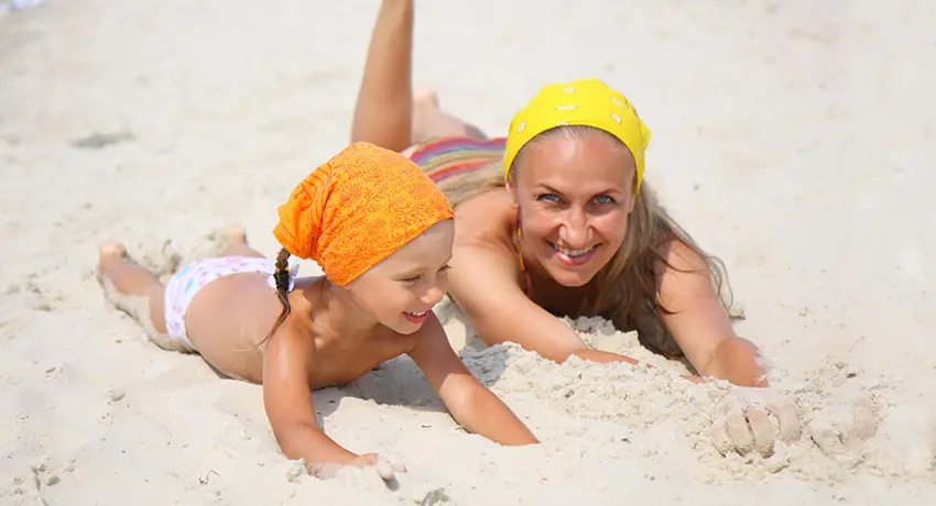 Kvinna och barn ligger i sanden