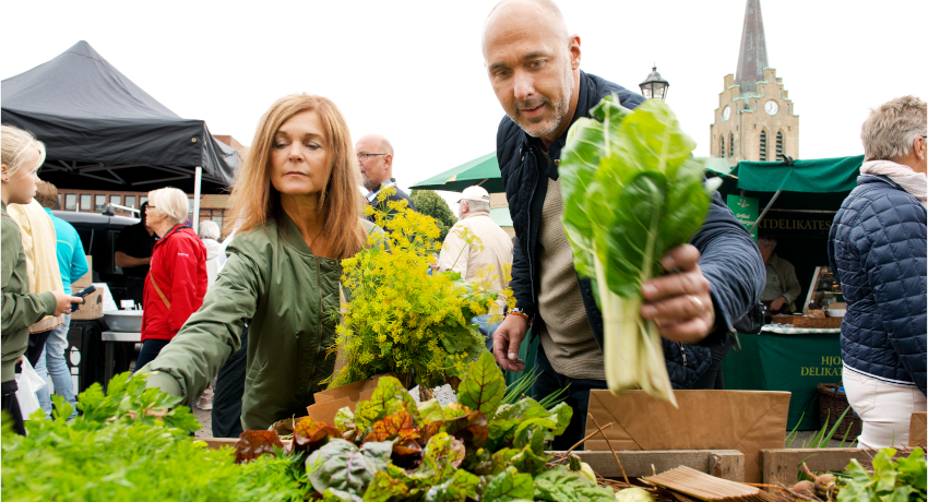 Två personer plockar grönsaker på en grönsaksmarknad