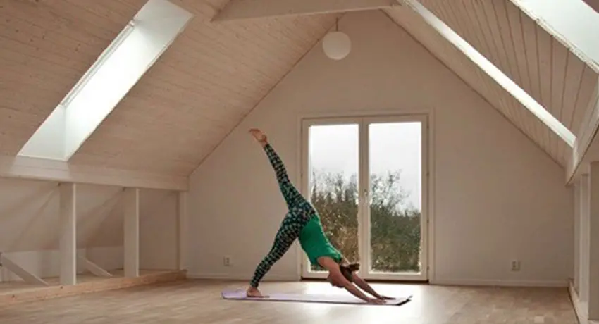 Person utövar yoga i ett vitt rum med utsikt över skogen