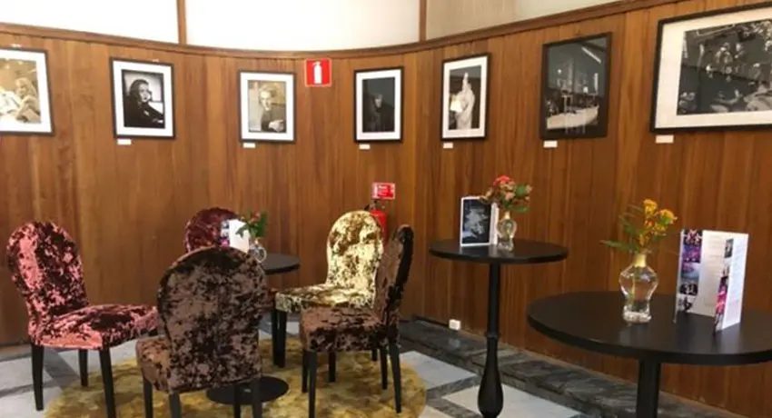 Konstutställning på väggen med bord och stolar i förgrunden