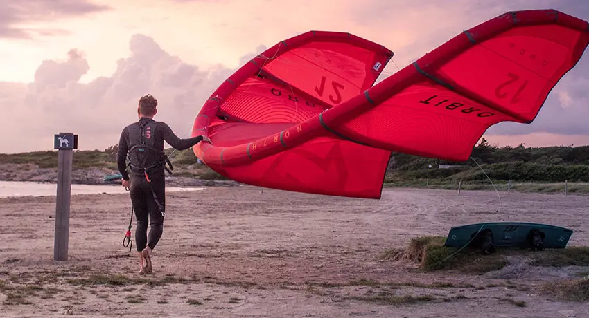 Surfare bär sin kite på en strand i Halmstad