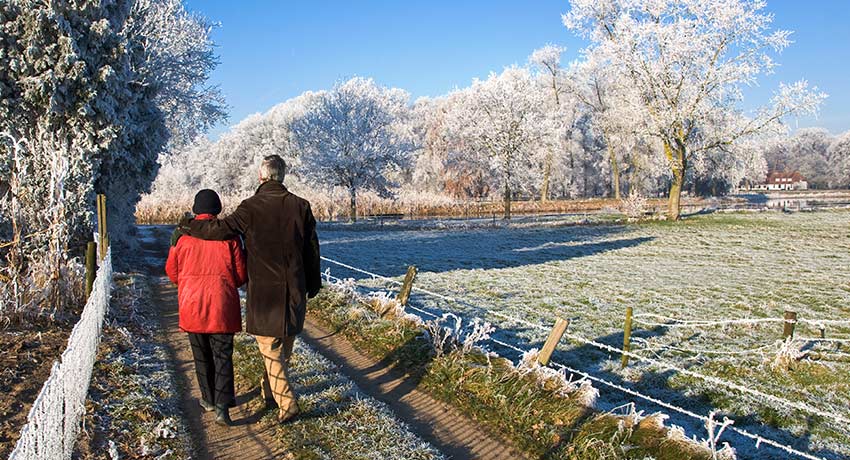 Äldre par ute och går i frostklädd natur