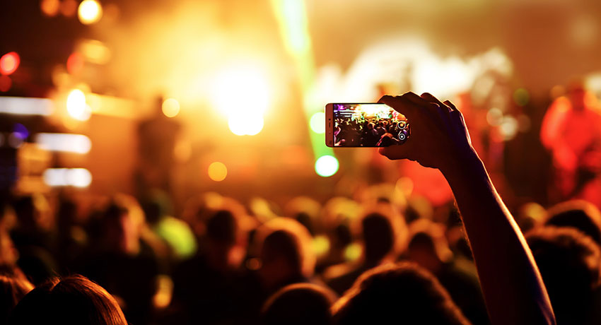 Hand holds up phone and films during concert